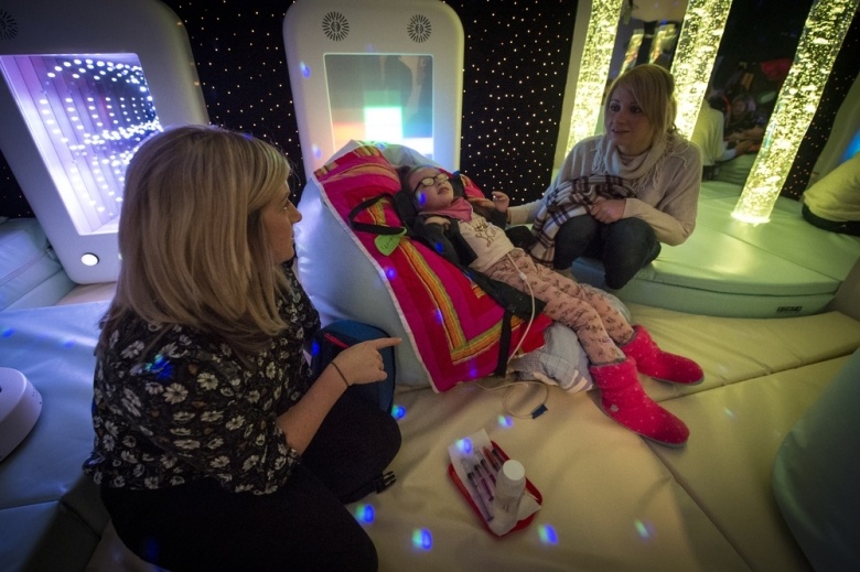 Little girl in sensory room with mum and carer