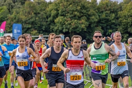 Group of runners running on green grass