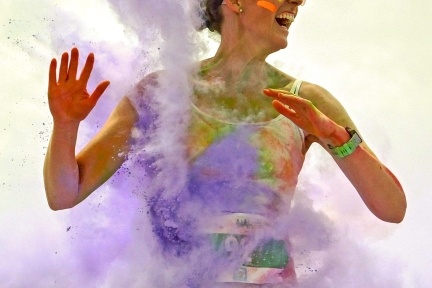 Woman smiling and being spattered with purple powder paint