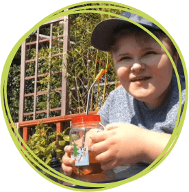 Boy wearing a cap sitting in his garden.