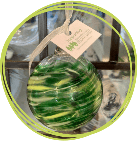 Green coloured glass bauble hanging from white ribbon