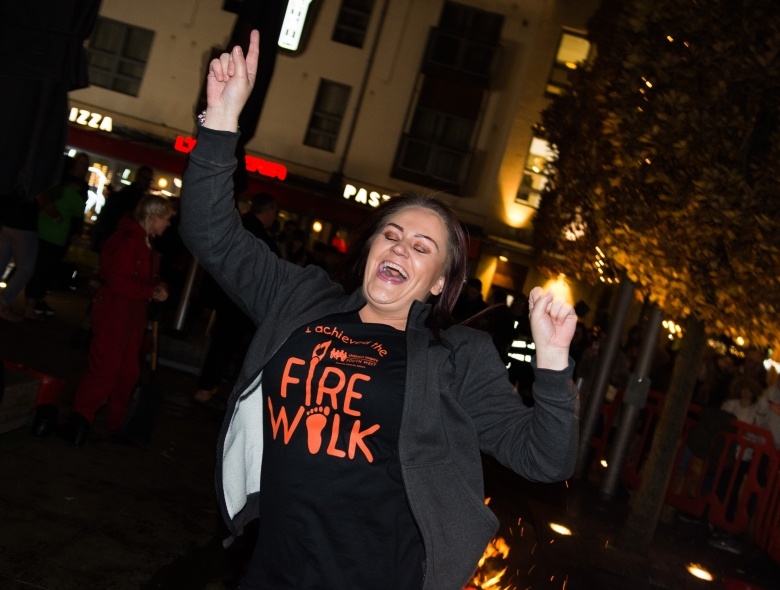 A Firewalk event participant smiling with hands in the air