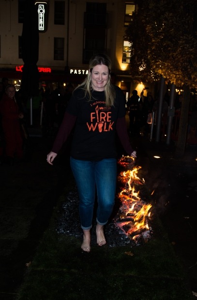 Woman wearing Firewalk t-shirt walking along hot coals