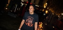 Woman wearing black Firewalk t-shirt smiles as she finishes her walk along hot coals thumbnail