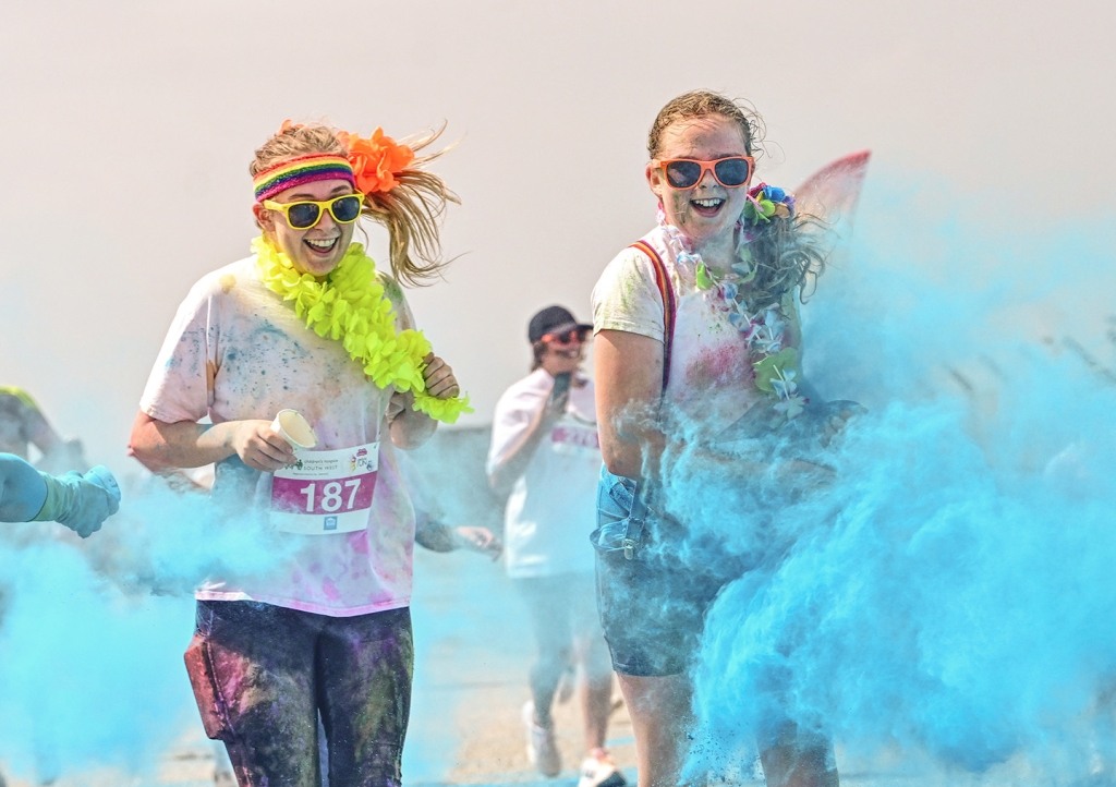 People having paint thrown at them whilst smiling and walking