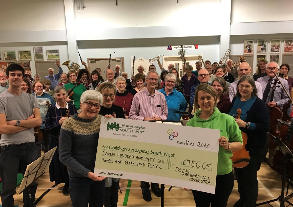 Members of the Devon Philharmonic Orchestra present the money raised to Children’s Hospice South West community fundraiser Laura Robertson