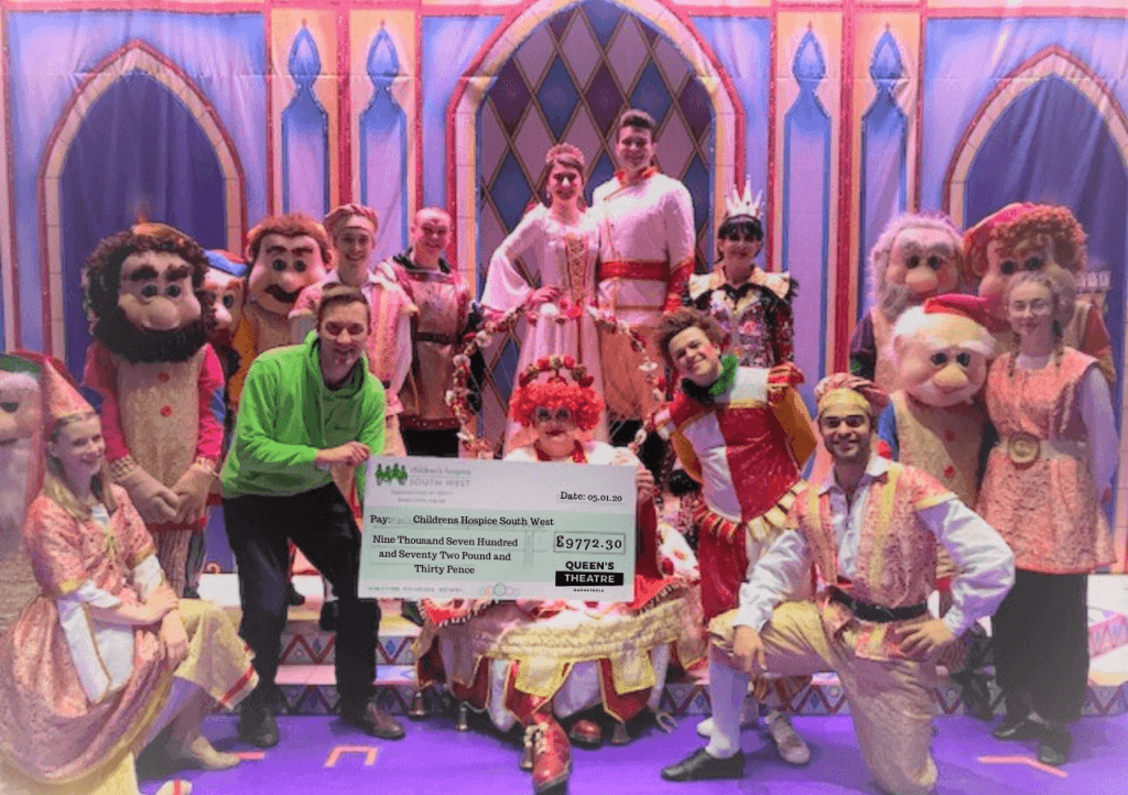 CHSW community fundraiser Neville Pope accepts the cheque from the cast of Snow White and the Seven Dwarfs at the Queen’s Theatre in Barnstaple