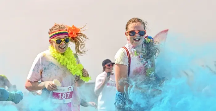 People having paint thrown at them whilst smiling and walking